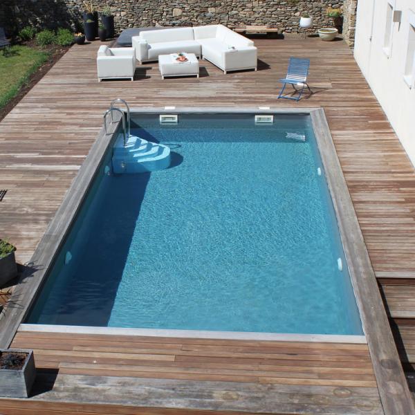 Piscine rectangulaire entourée d'une terrasse en bois dans un jardin de la région toulousaine