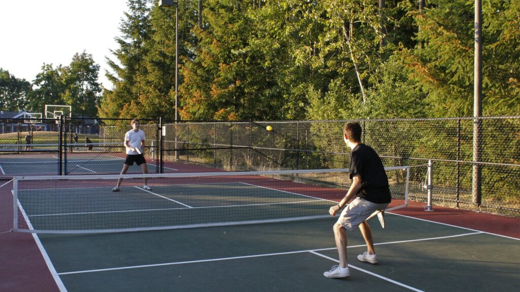 Deux joueurs disputent une partie de pickleball sur un terrain extérieur